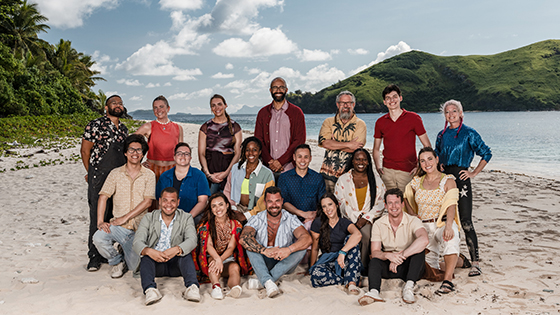 The cast of Survivor poses on a beach.