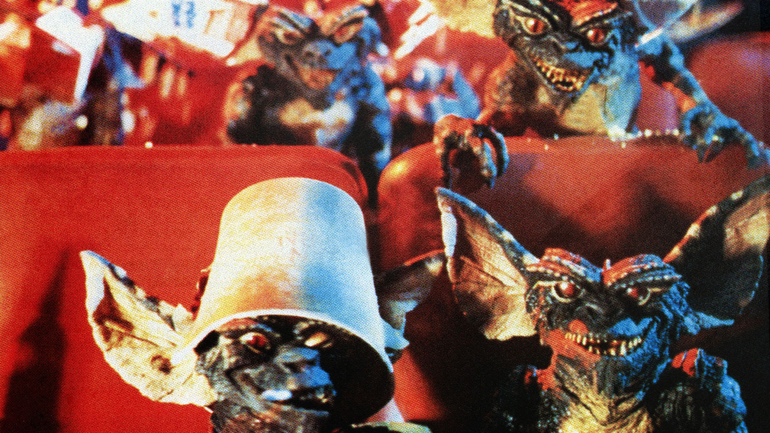 Gremlins sitting in movie theater seats.
