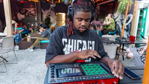 A man has headphones on as he mixes beats on an MPC.