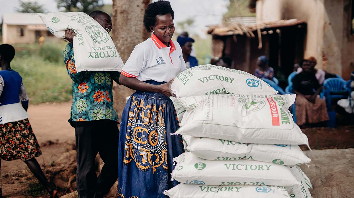Food packages being carried into a pile for food distribution.