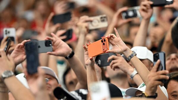 A crowd of spectators takes photos with their smartphones.