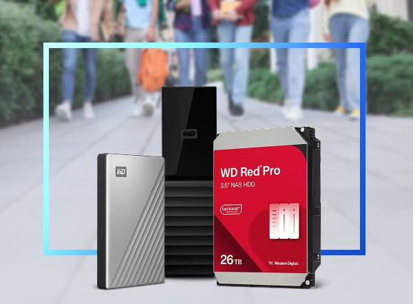 Three Western Digital storage devices, including a portable hard drive, a My Book desktop storage, and a WD Red Pro 26TB NAS HDD, set against a blurred background of people walking.