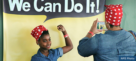 A little girl poses as Rosie the Riveter, complete with a red, polka dot bandana, at Rosie the Riveter World War II Home Front National Historical Park