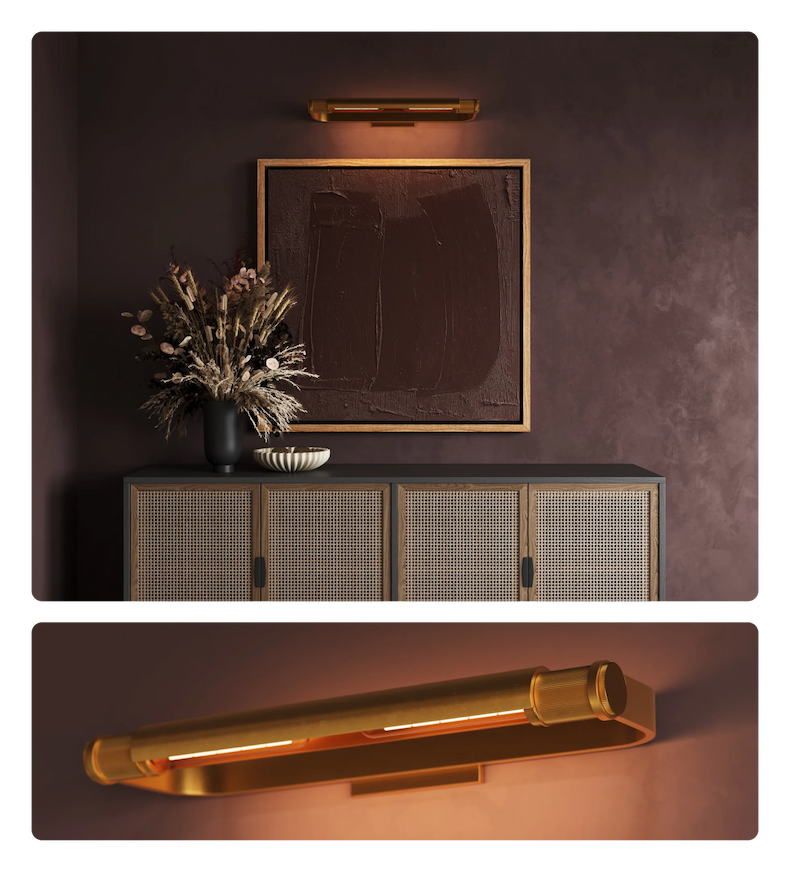 A gold linear picture light illuminating a dark abstract painting above a woven sideboard.