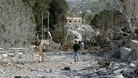 People walk among rubble.