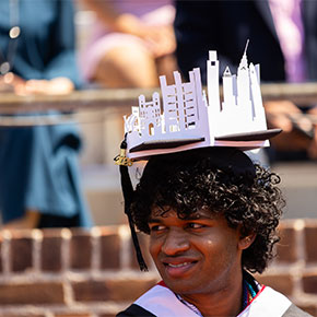 A student wearing a custom graduation cap that holds a paper cutout of the Philadelphia skyline.