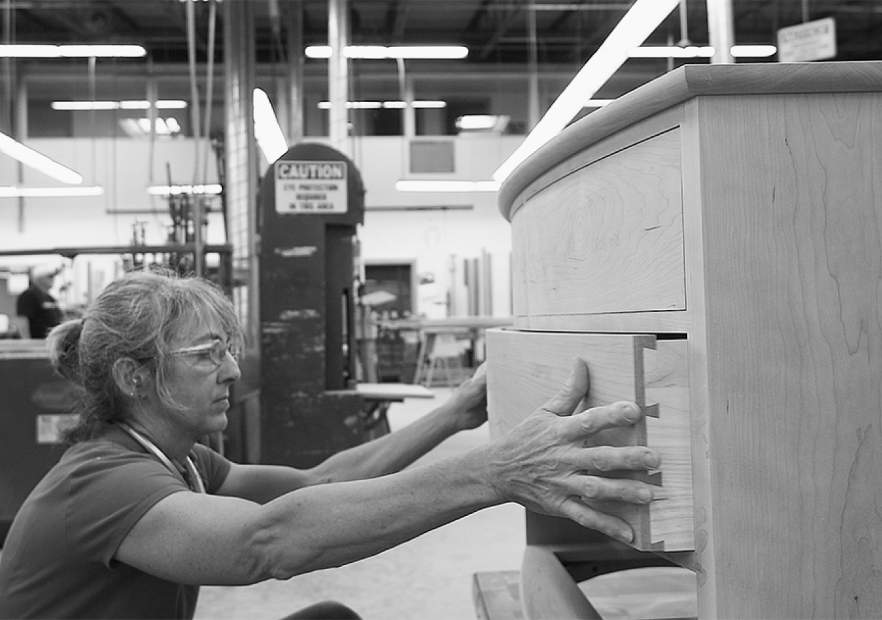 Brenda works on fitting the drawer of a crescent dresser. 