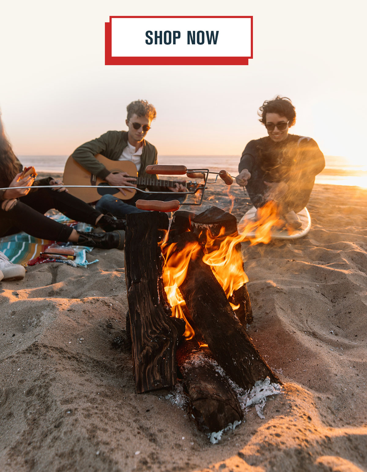 People on the beach roasting hot dogs over a fire and playing guitar. Shop Now CTA