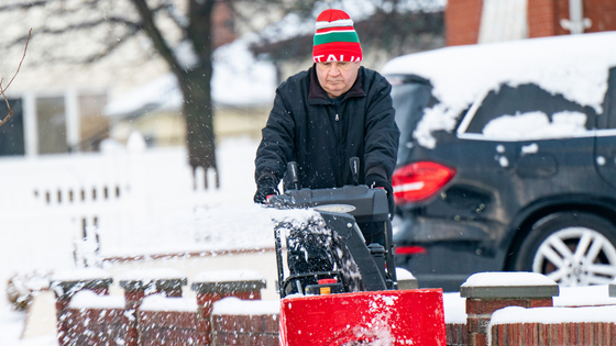 A man in a hat clears snow from the sidewalk