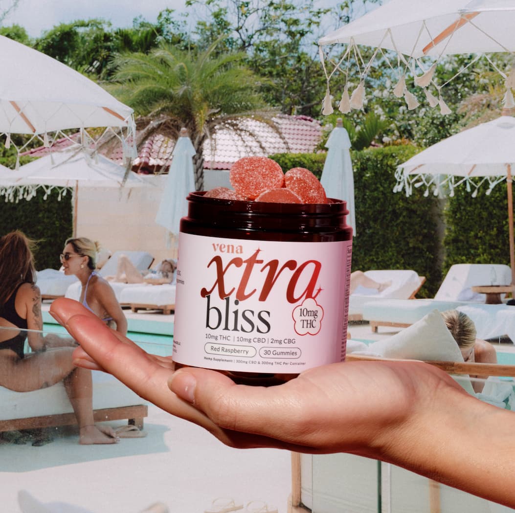 Image of people socializing near a pool with an Xtra Bliss Gummy jar in the foreground. 