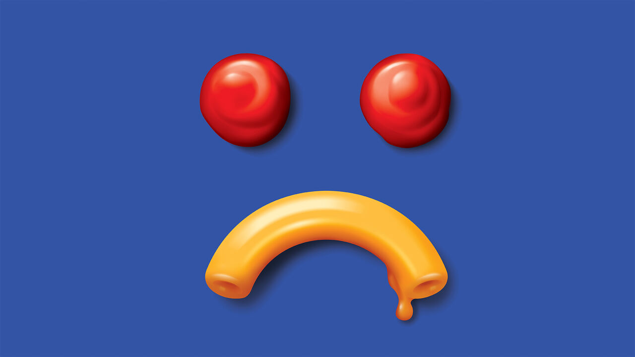 A sad smiley face made of ketchup and macaroni and cheese. 