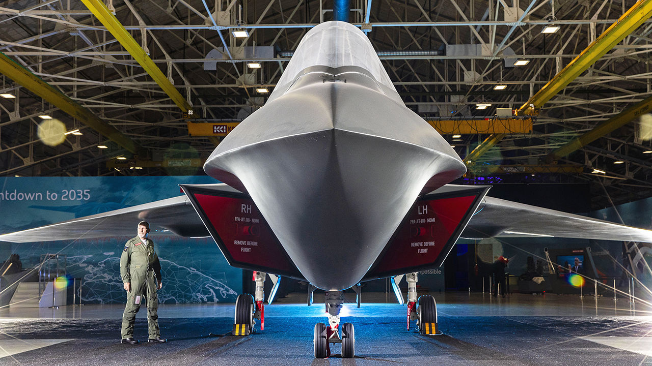 A man stands under the wing of a model of Tempest, which will be the next-generation RAF fighter jet. 