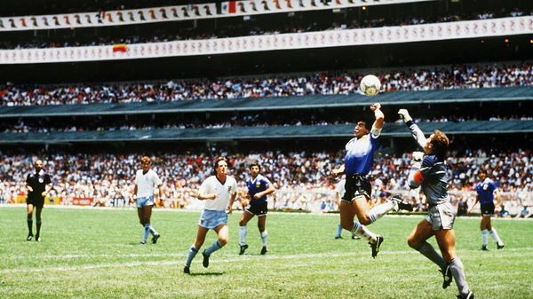 Diego Maradona of Argentina handles the ball past Peter Shilton of England to score the opening goal of the World Cup Quarter Final. 1986