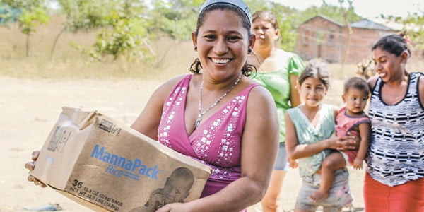 A mother holds a box of food she received after a natural disaster.