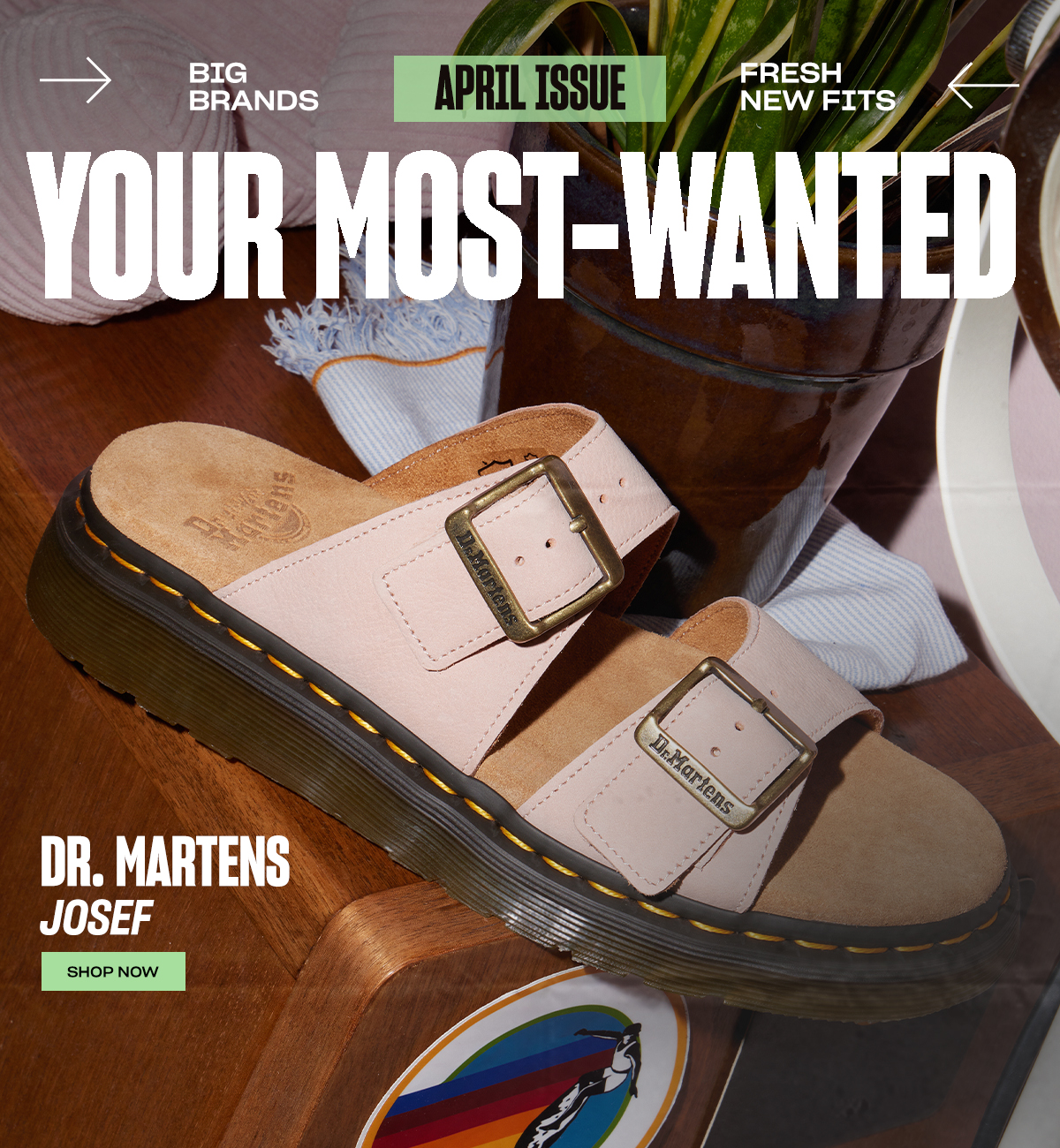 An image of a pink Dr. Martens sandal on a side table alongside a plant. The image contains the text 'Big Brands April Issue Fresh New Fits. Your Most-Wanted. Dr. Martens Josef. Shop Now'