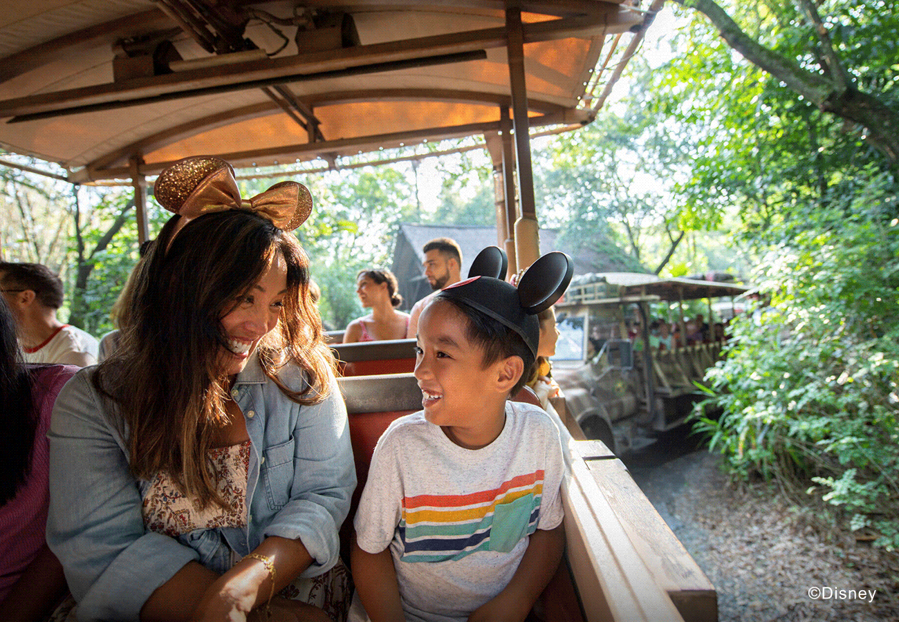 A hero GIF featuring 3 images: 1) A Mother and son in mouse ear hats on a safari ride. 2) A mother and daughter play in a fountain pool under stone arches. 3) A couple enjoying a meal in a warm restaurant setting.