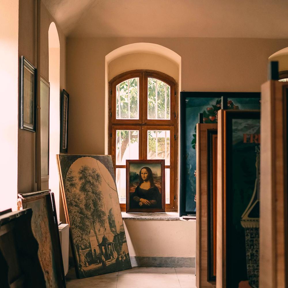The Mona Lisa sits at the back of a sunny art storage room filled with paintings. 