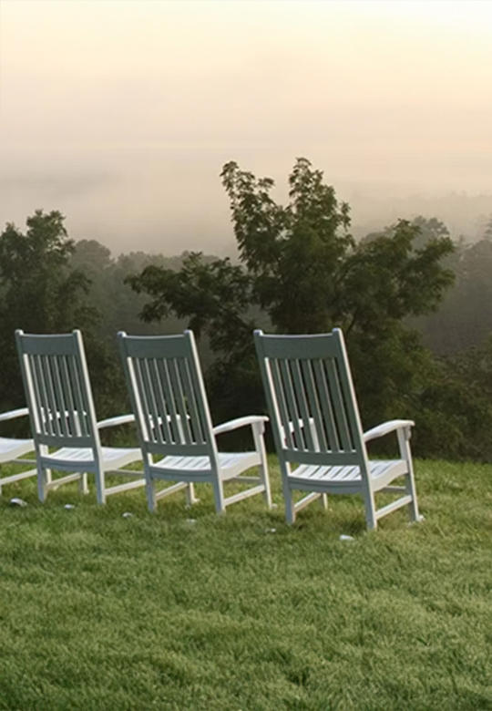 A row of rocking chairs overlook a misty mountain landscape. Check out Blackberry Farm.