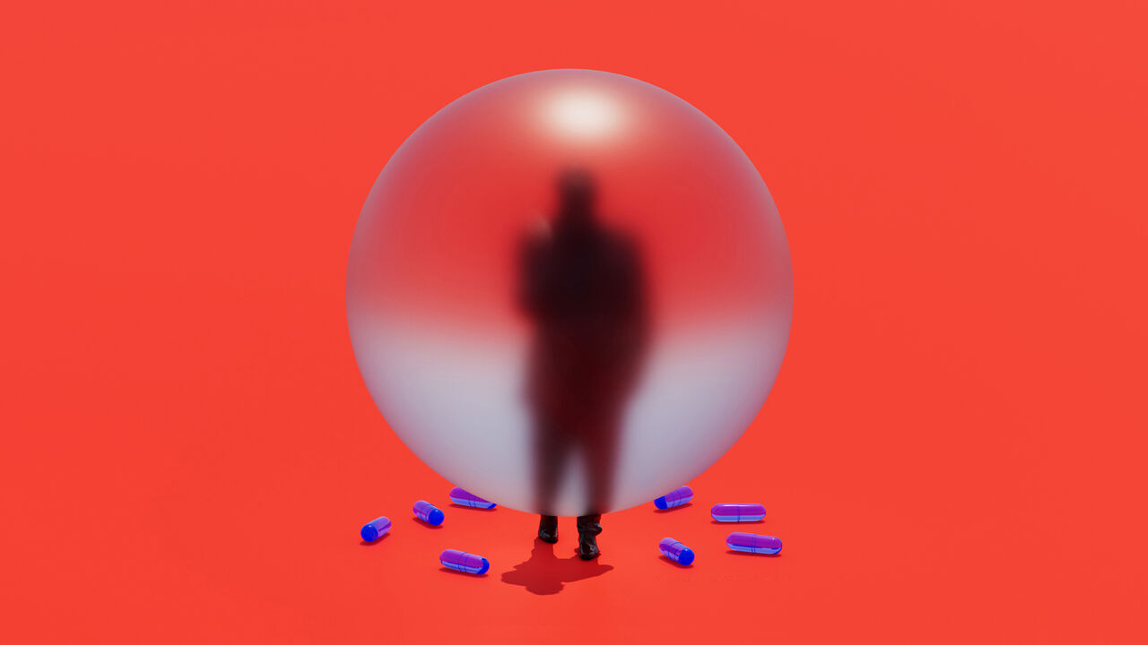 Silhouette of a man against a red background obscured by a sphere. There are blue pills scattered on the floor