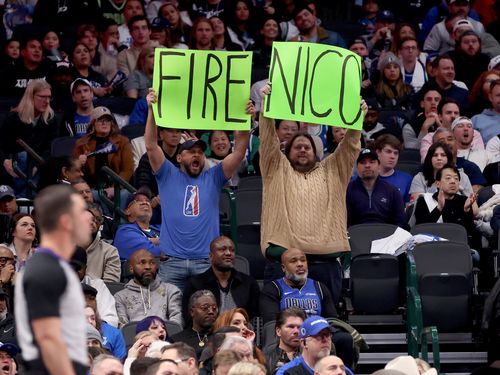 Two people in a full arena holding a sign that says FIRE NICO.