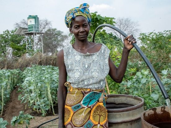 Alt-text: Manga, a mother of four in Zambia, stands in the garden she grew thanks to CMMB supporters