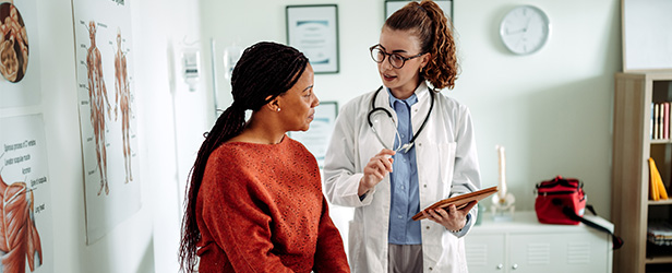 Healthcare provider consulting with a patient in an exam room.
