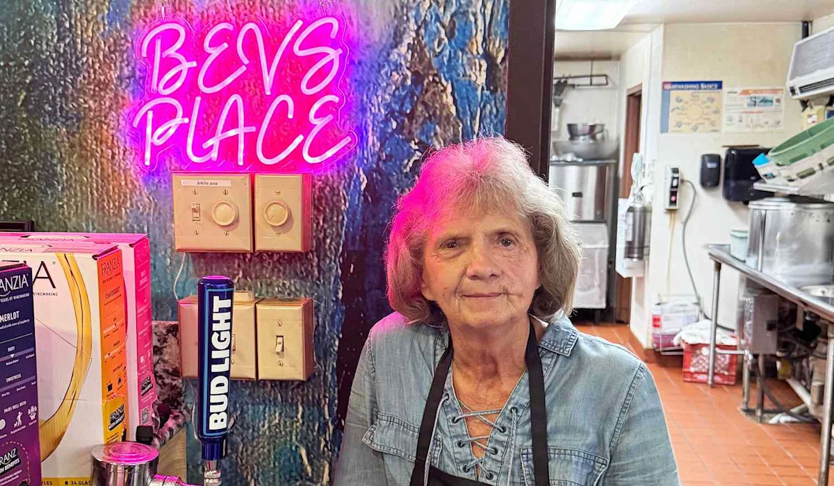 A woman stands in front of a neon sign.