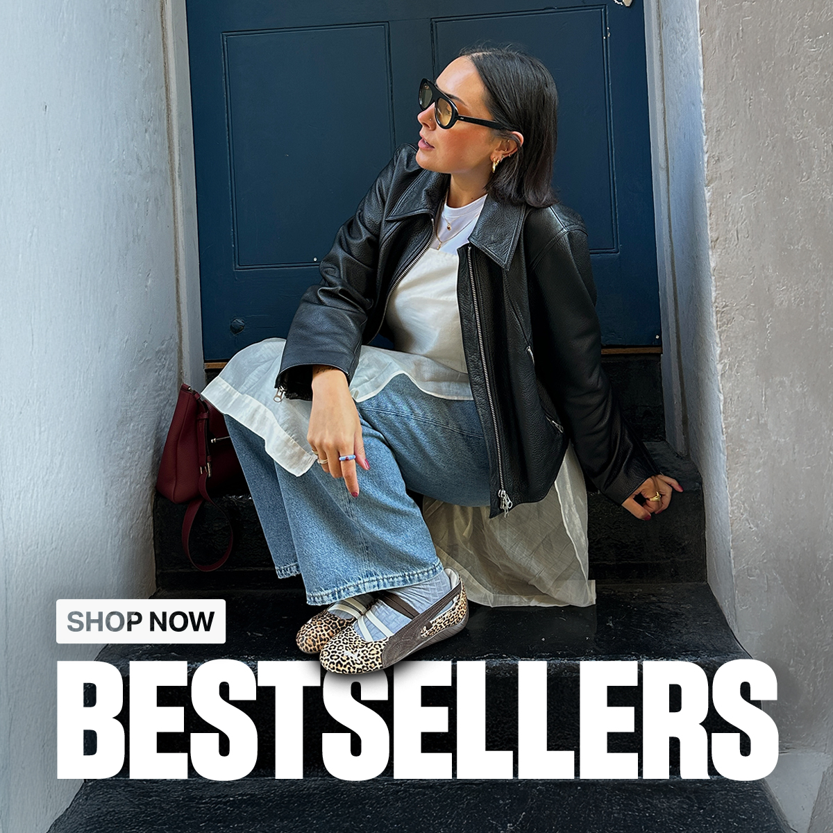 A n image of a person on an outdoor step wearing leopard print PUMA Speedcat Ballet shoes, a leather jacket and blue jeans. The image contains the text 'Bestsellers. Shop Now'