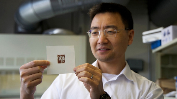 man holds a card with a small copper circuit printed on it
