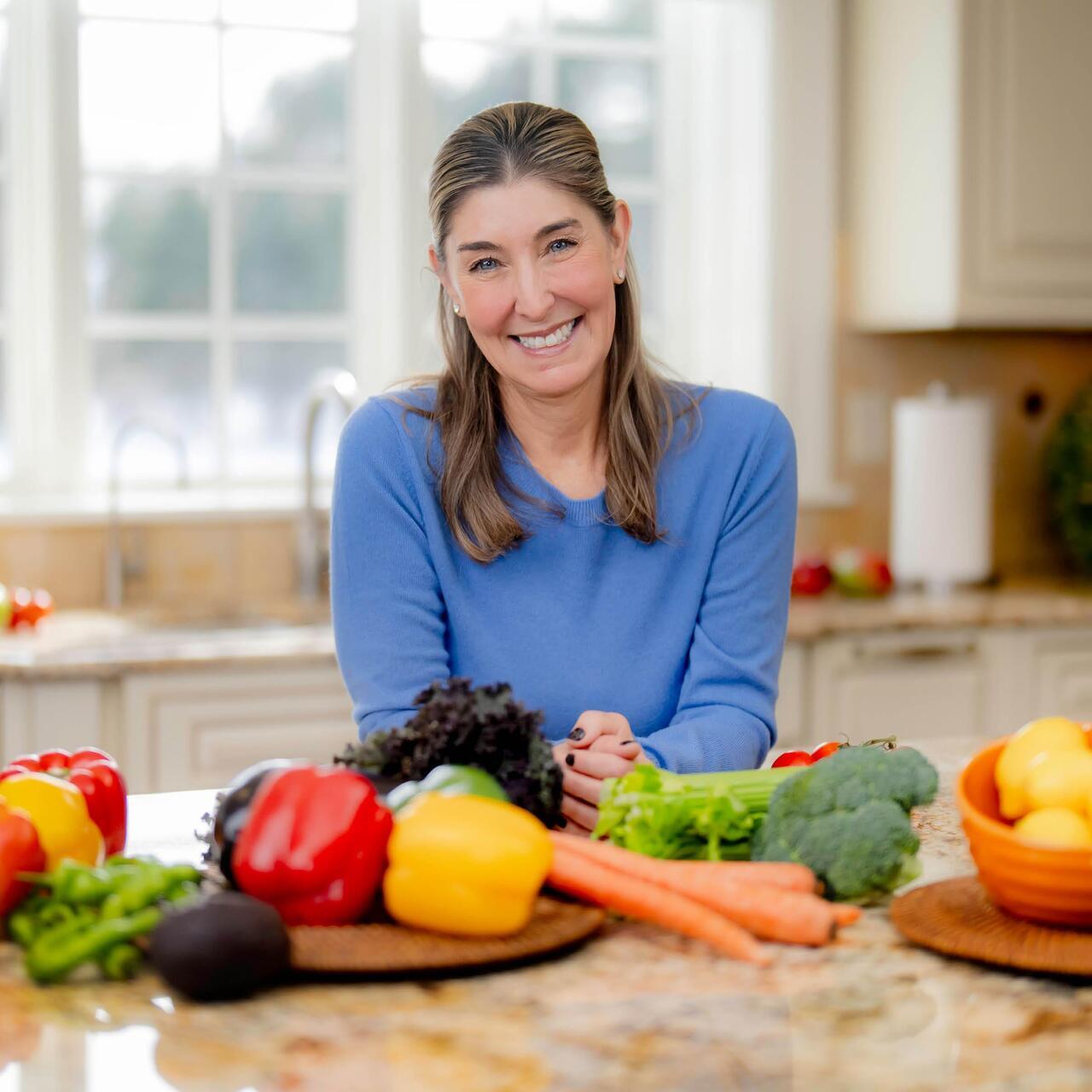 Andrea Antino stands in her kitchen with fresh vegetables on the counter as she reflects on how nutrition and lifestyle became an important part of her colon cancer journey.