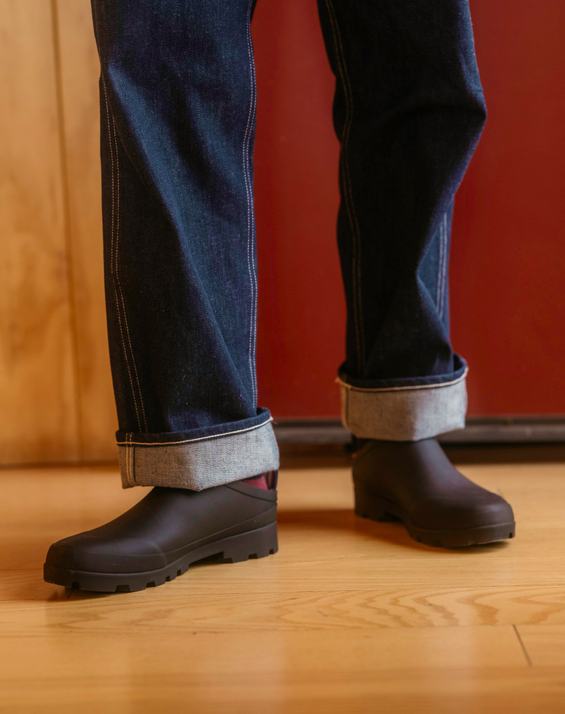 Guy wearing dark cuffed denim pants and balck bodega clogs