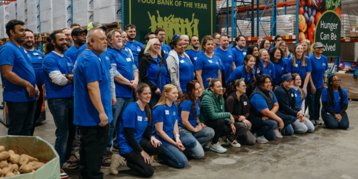 Group of volunteers in blue shirts pose for a photo