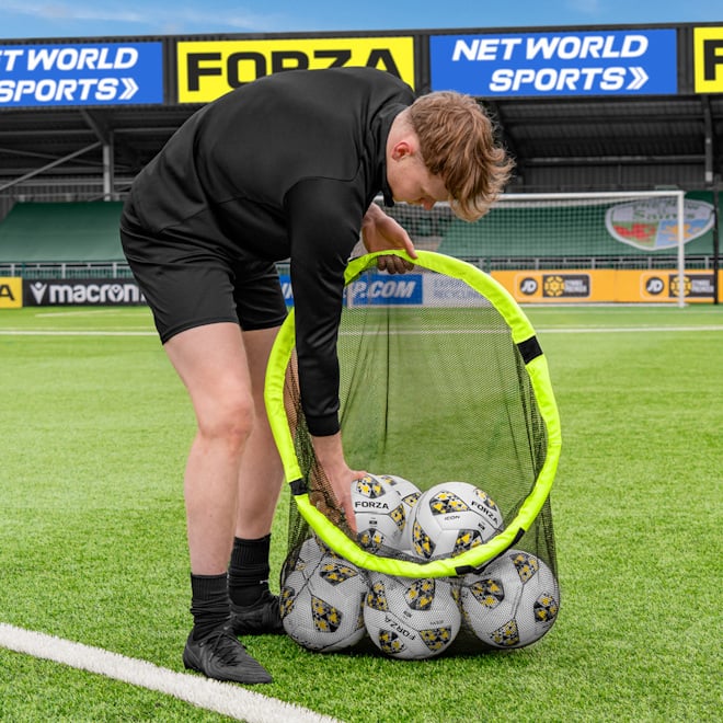 Coach on a pitch adding balls into the FORZA Football Target Net & Ball Bag.