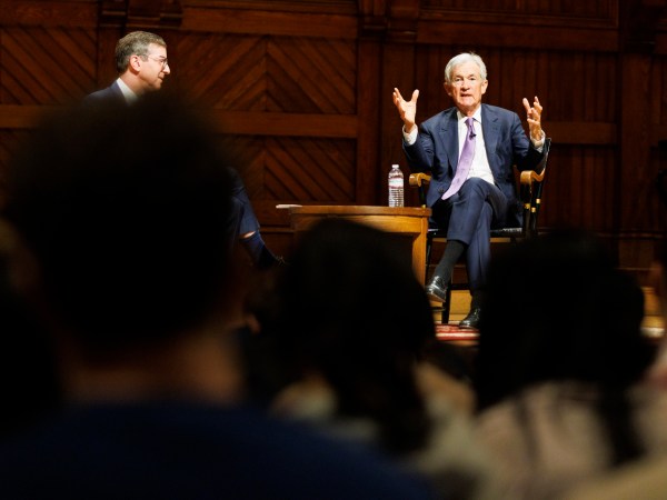 Jerome Powell (right) speaks to a class in Sanders Theatre. He was joined by David Laibson,