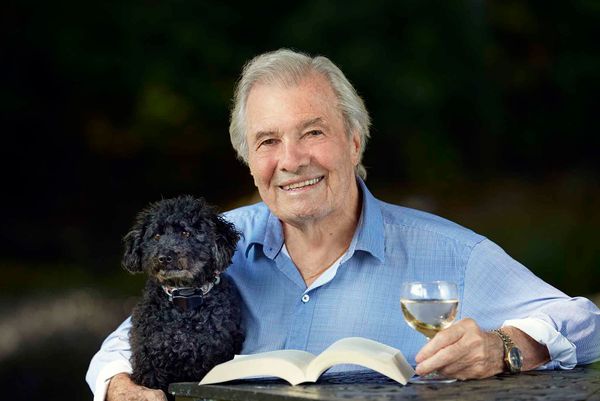 Photo: Jacques Pépin with his little black curly dog and a glass of white wine.