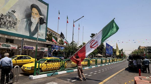 A worker raises a pole bearing the Iranian flag at Enghelab Square in Tehran