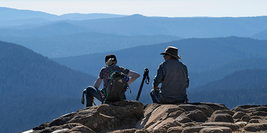 Two visitors overlooking a mountain landscape in a national park