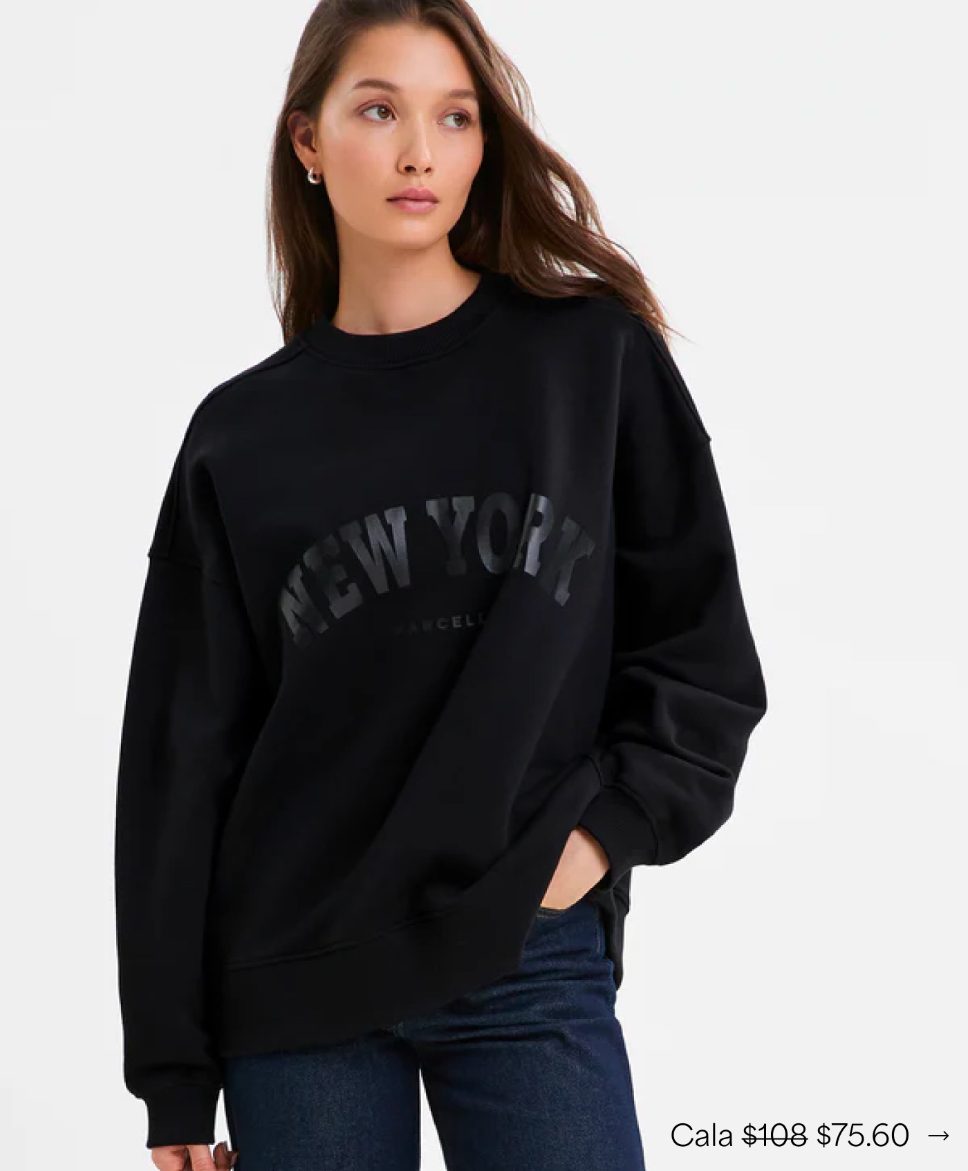 Yada in The Cala NYC Sweatshirt looks to the side with one hand in her pocket.