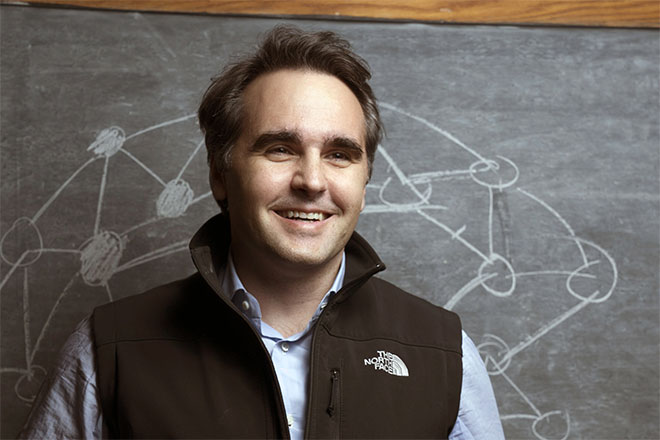 Damon Centola in front of a chalkboard.