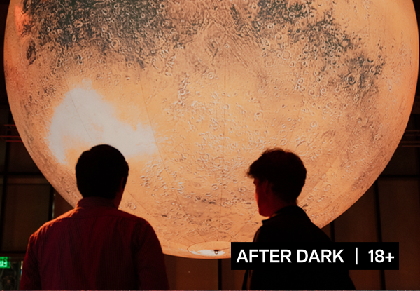 A silhouette of two people standing in front of an inflatable Mars. 
