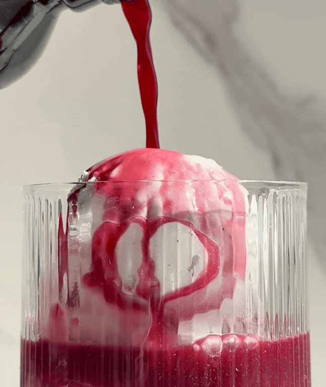 A GIF of Curious Red being poured into a glass over scoops of vanilla ice cream.