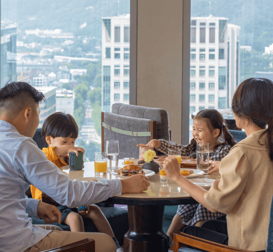 A family enjoying breakfast together, with a large scenic view of the city core.