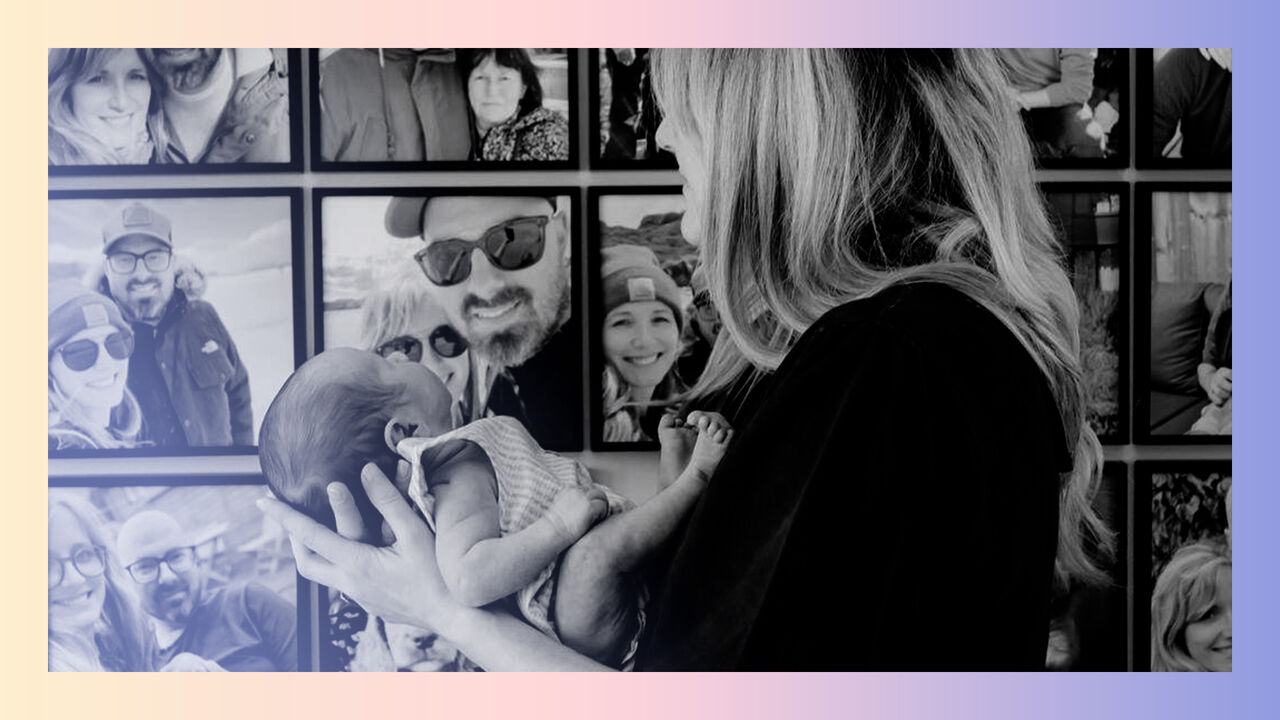 A child and mother in front of a wall of family photographs