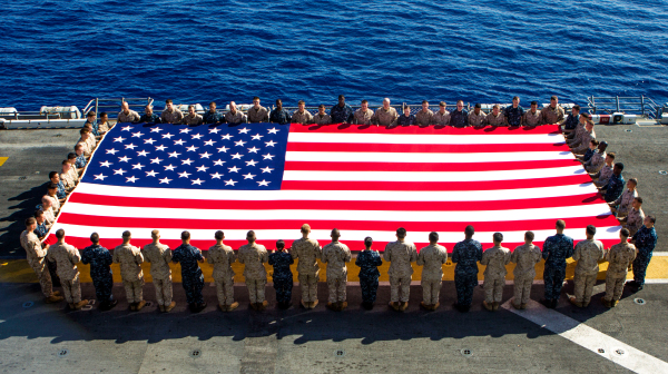 Service members work together to carry American flag