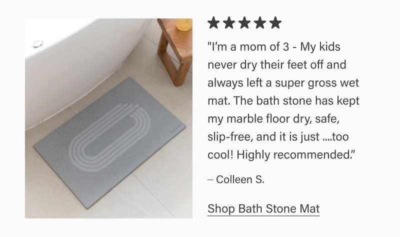 Gray Dorai bath stone mat placed beside a bathtub on tile flooring. Five-star review reads: “I’m a mom of 3… The bath stone has kept my marble floor dry, safe, slip-free… Highly recommended.” – Colleen S. Text link: “Shop Bath Stone Mat.”