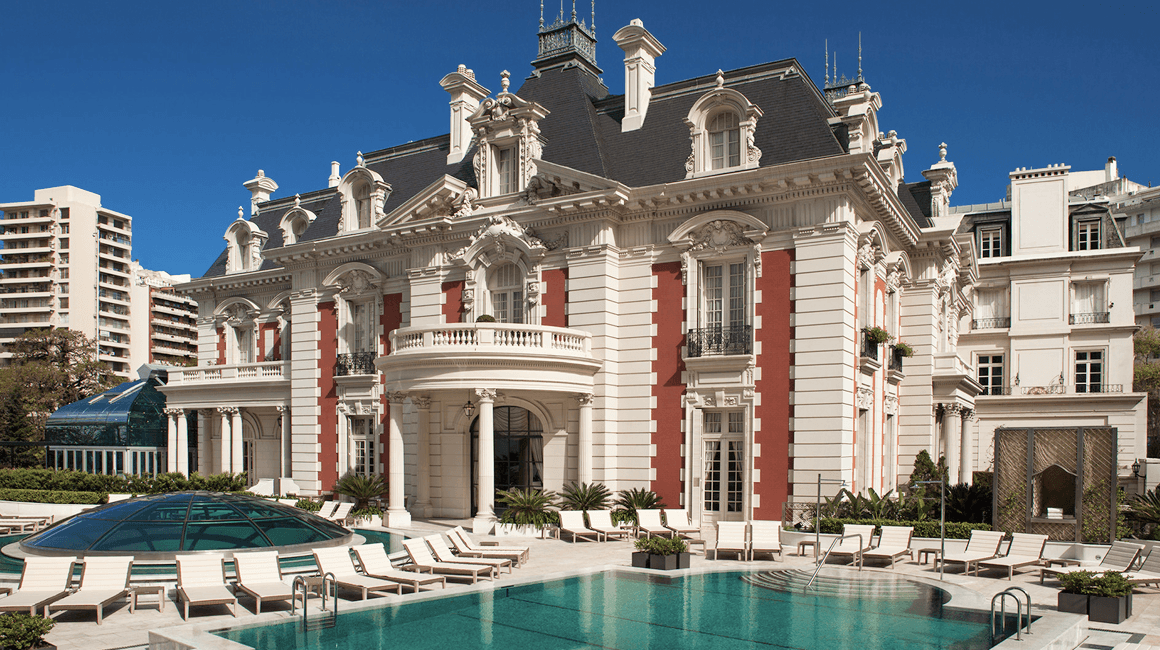 A stately white hotel with an outdoor pool.