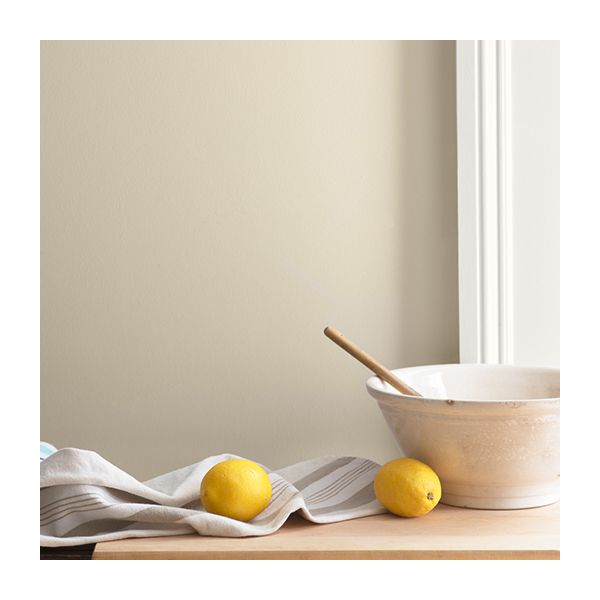 A light beige painted wall with white molding, behind a mixing bowl and lemons on a tabletop.