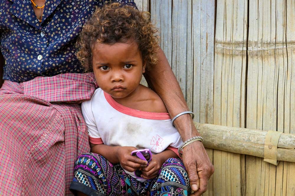 A girl sits in front of her home.