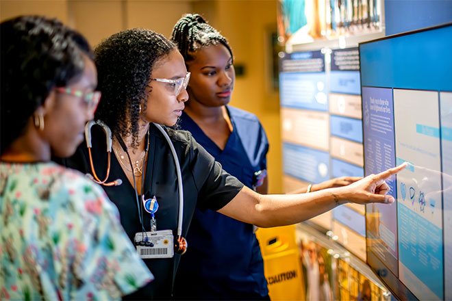 Several nurses look at a screen in a hospital.