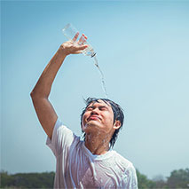 A person splashes a water bottle on themselves.